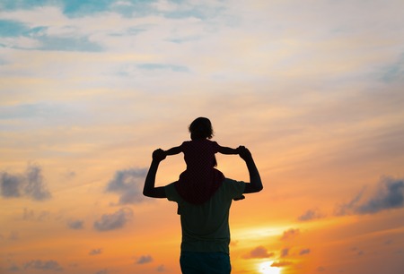 Father and little daughter silhouettes play at sunsetの写真素材