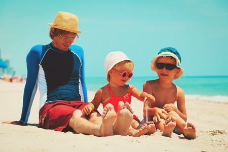 father with son and daughter play on beachの写真素材