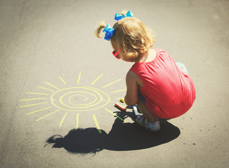 little girl drawing sun on asphaltの写真素材