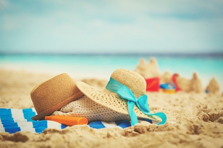 hats, bag, suncream and glasses on beachの写真素材