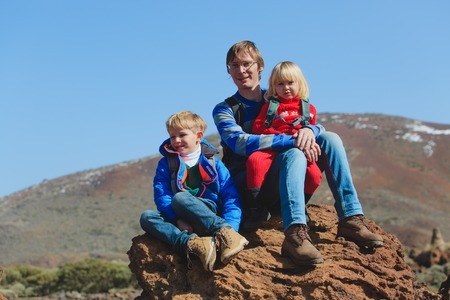 father with two kids hiking in mountainsの写真素材