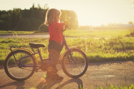 little girl riding bike at sunsetの写真素材