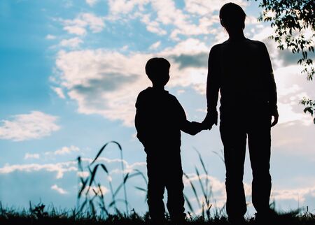 silhouette of father and son holding hands at sunsetの写真素材