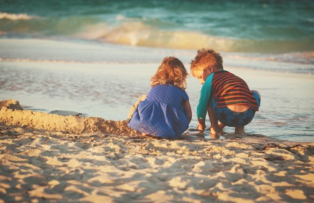 little boy and girl play with sand on beachの写真素材