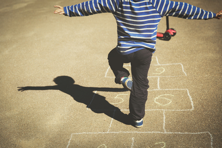 little boy playing hopscotch on playgroundの写真素材