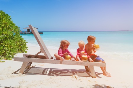 little boy and two girls drinking coconut on beachの写真素材