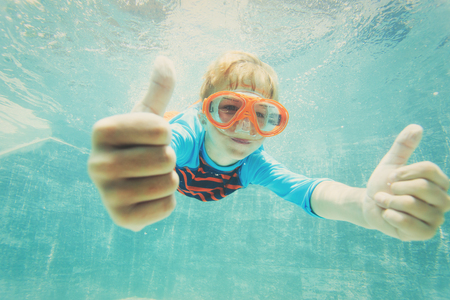 happy boy swimming underwater with thumbs upの写真素材