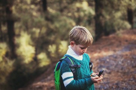 little boy travels with compass in green forestの写真素材