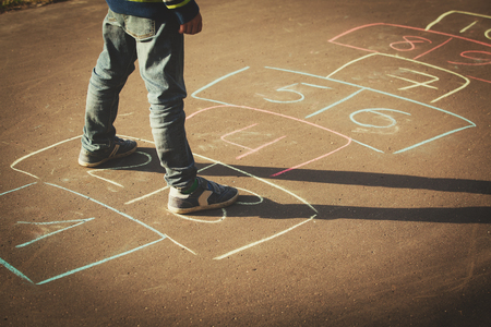 little boy playing hopscotch on playgroundの写真素材