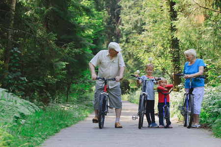 active senior couple with kids riding bikes in natureの写真素材