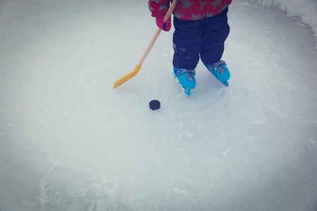 little girl learn to play hockey skating on ice in winterの写真素材