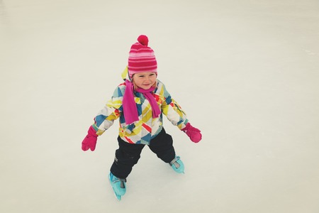 happy little girl learning to skate in winterの写真素材