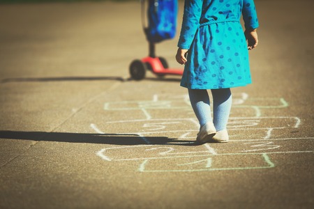 little girl playing hopscotch on playgroundの写真素材