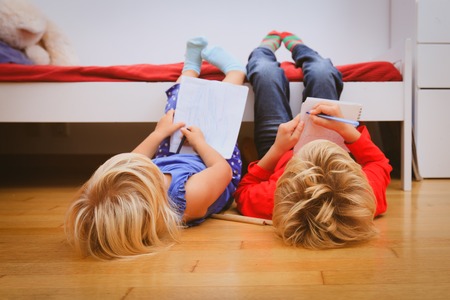little boy and girl draw, pretend to do homework in playroomの写真素材