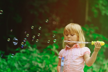 cute little girl blowing soap bubbles