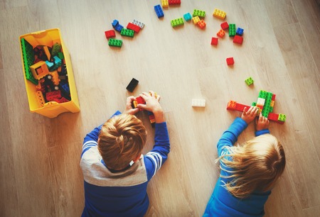 little boy and girl play with plastic blocks