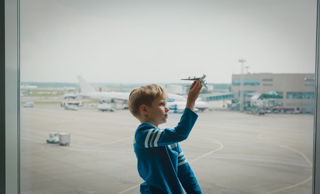 boy playing with toy plane while waiting in airportの写真素材