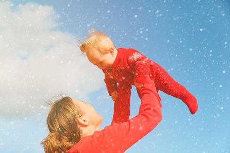 mother and happy little daughter play at winter skyの写真素材