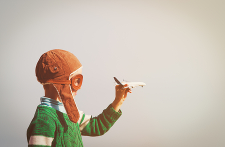 little boy with helmet and glasses play with toy plane on skyの写真素材