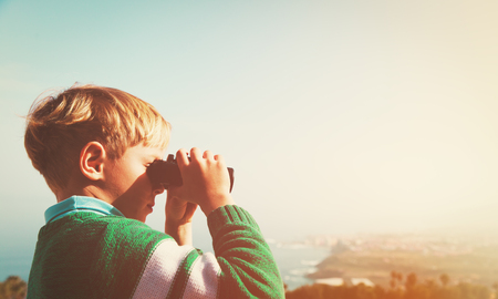 little boy looking through binoculars, travel conceptの写真素材