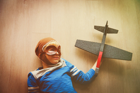 little boy with helmet and glasses play with toy planeの写真素材