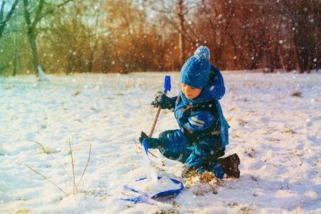 little boy dig and play in snow winter natureの写真素材