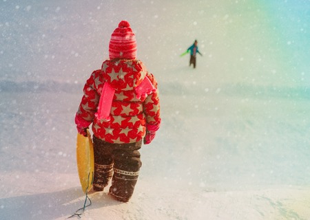 kids winter fun- little girl and boy sliding in snow