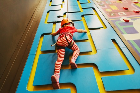 little girl climbing wall in sport centerの写真素材