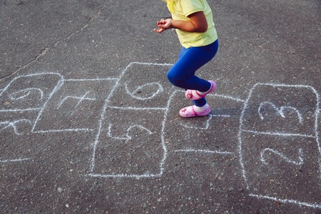 little girl playing hopscotch on playgroundの写真素材