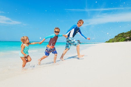 father with kids play with water run on beachの写真素材