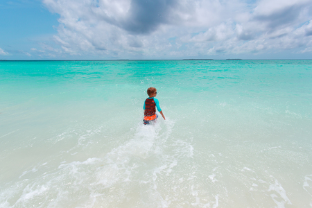 little boy go swim on tropical beachの写真素材