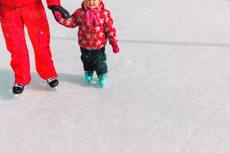 father and little daughter learning to skate in winterの写真素材