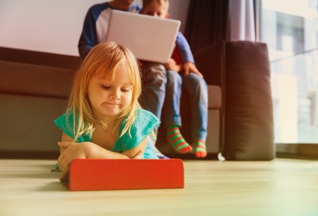 father and kids looking at laptop and touch pad at homeの写真素材