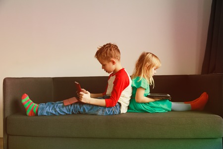 little boy and girl looking at touch pad at homeの写真素材