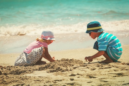 little boy and girl play with sand on beachの写真素材