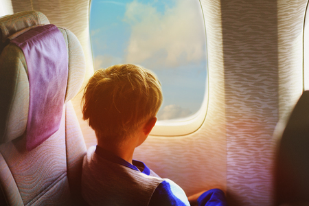 little boy travel by plane looking through windowの写真素材