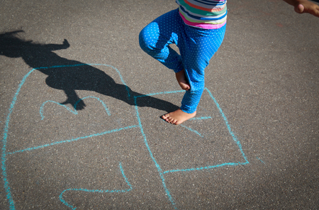 little girl playing hopscotch on playgroundの写真素材
