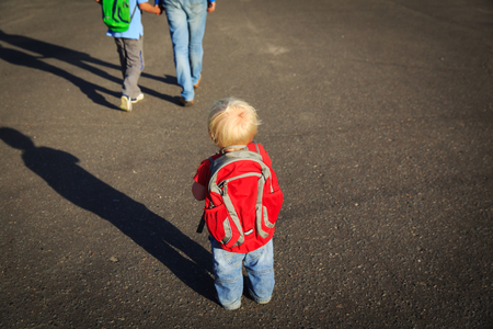 little girl with backpack looking at father and brother going to schoolの写真素材
