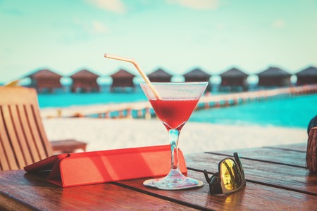 cocktail, touch pad and sun glasses on beach vacationの写真素材