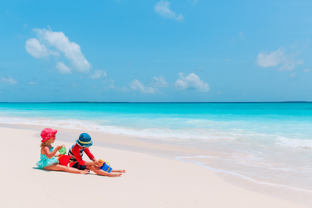 little boy and girl play with sand on beachの写真素材