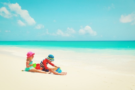 little boy and girl play with sand on beachの写真素材
