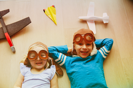 happy kids with helmet and glasses play with toy planeの写真素材