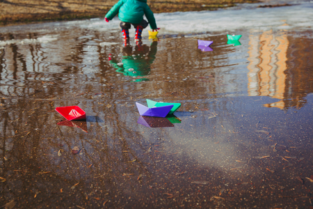 child playing with paper boats in water puddleの写真素材
