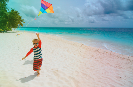 Little boy flying a kite on tropical beachの写真素材