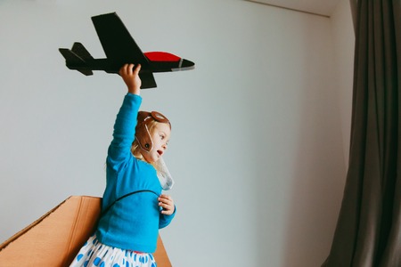little girl with pilot glasses and wings play fly at homeの写真素材