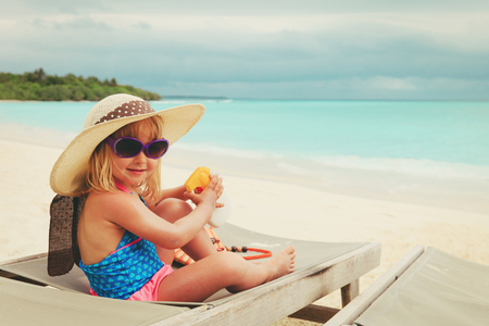 sun protection - little girl with suncream at beachの写真素材