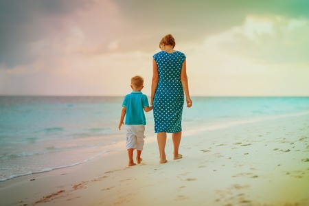 mother and son walking on sunset beachの写真素材