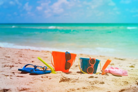 kids toys, shoes, sunglasses and bag on beachの写真素材