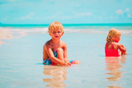 little boy and girl play with water on beachの写真素材