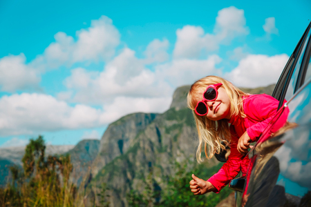 happy cute little girl travel by car in mountainsの写真素材